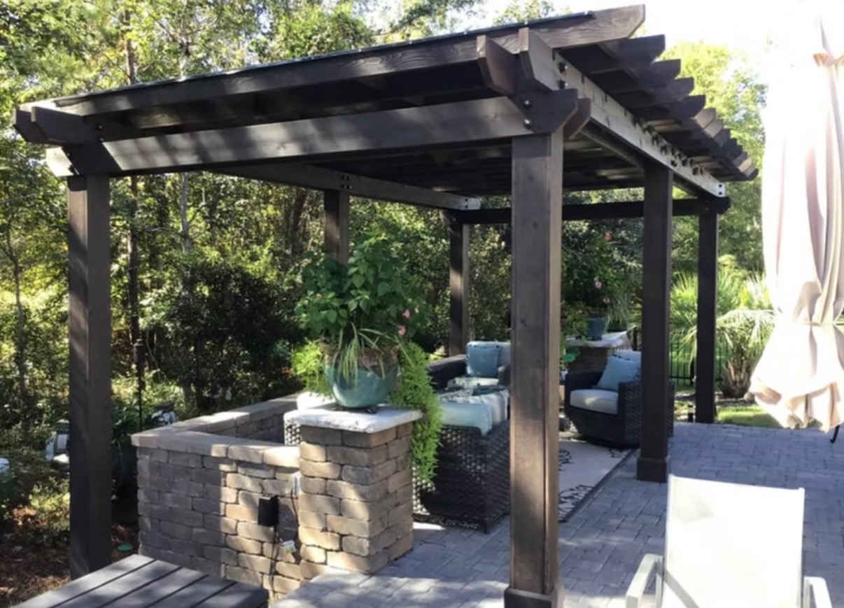 Custom dark-stained wood pergola over a stone patio